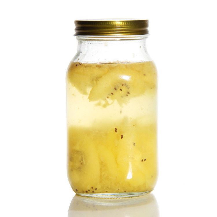 Un pot de thé en verre rond avec un couvercle en or
